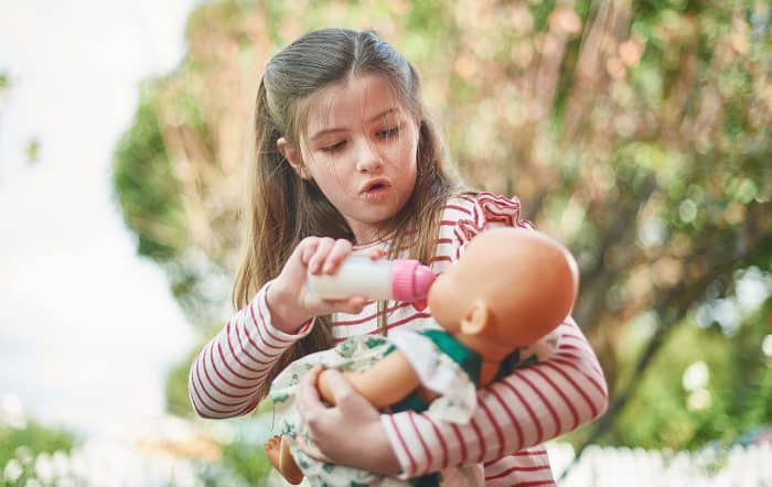 Positive effects of pretend play - girl plays with doll