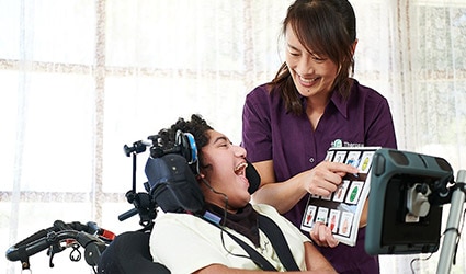 A customer uses an AAC device with their therapist