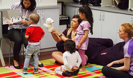Therapists and young children engage in a story book.