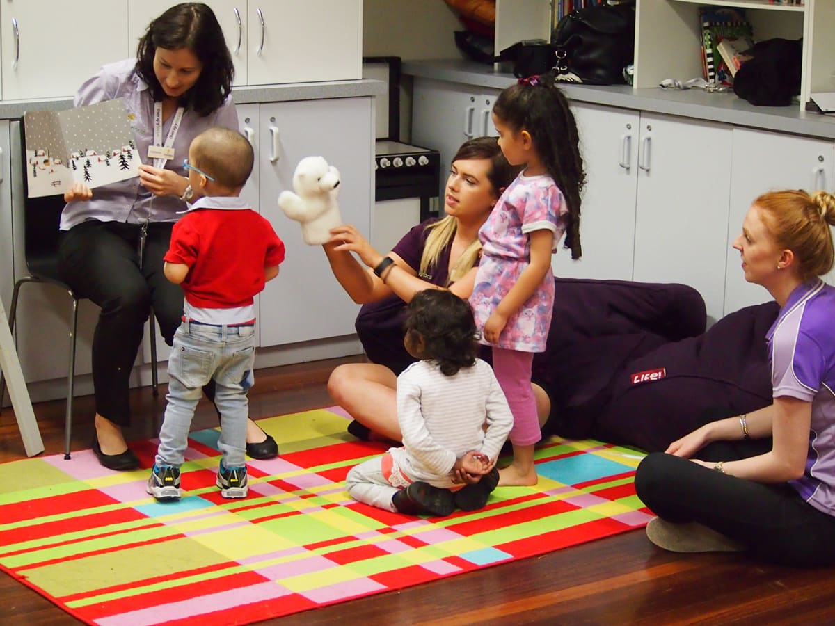 Therapists and young children engage in a story book.