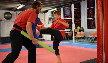Boy kicking leg in air with karate instructor