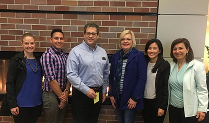 A group of clinicians and professionals stand together and smile.