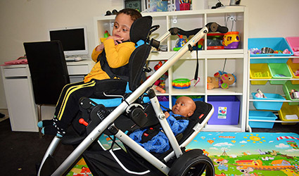 Toddler and baby in specially adapted double stroller