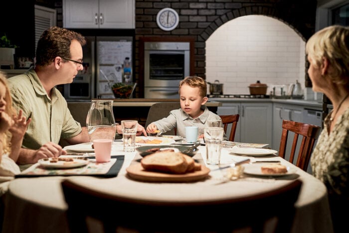 A boy at the dinner table with his family