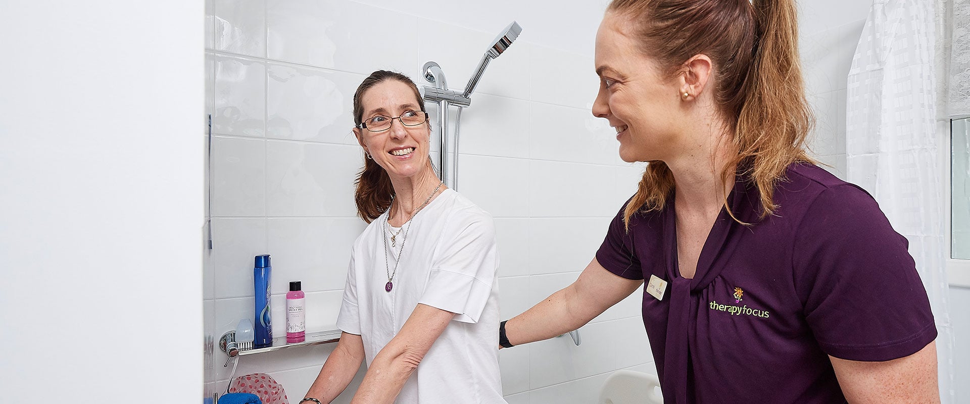 Therapist supports client holding shower rail in bathroom