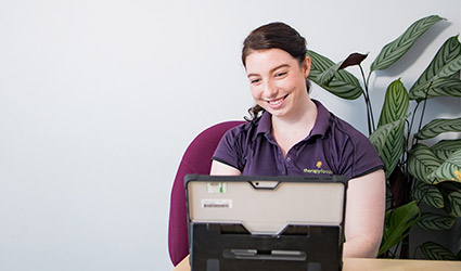 A therapist smiles at computer screen during a teletherapy session