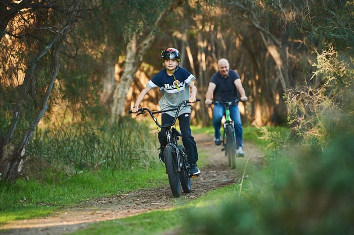 A boy and man riding through the bush