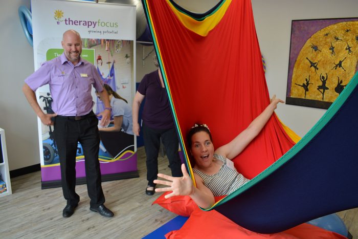 young woman in hammock laughing as therapist looks on