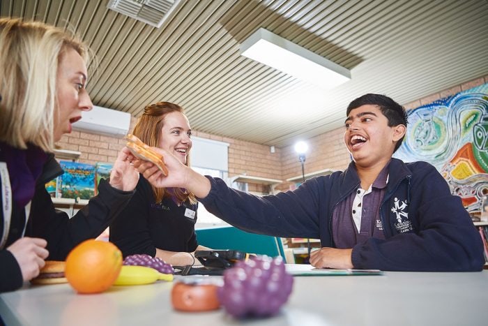 A boy using pretend food with two therapists