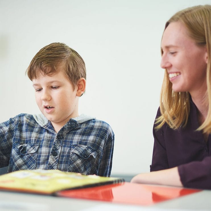 Boy picks up card as therapist looks on