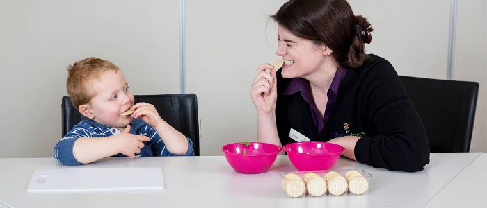 Therapy Focus therapist and young boy biting into crackers