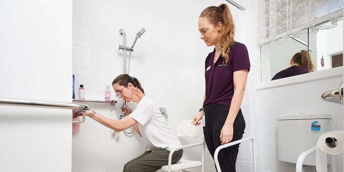 Client pulls herself from shower chair as therapist watches on