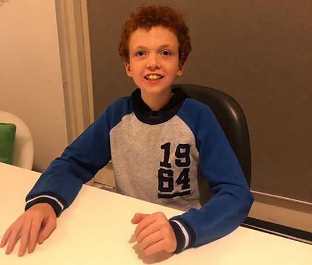 Boy sits at table smiling