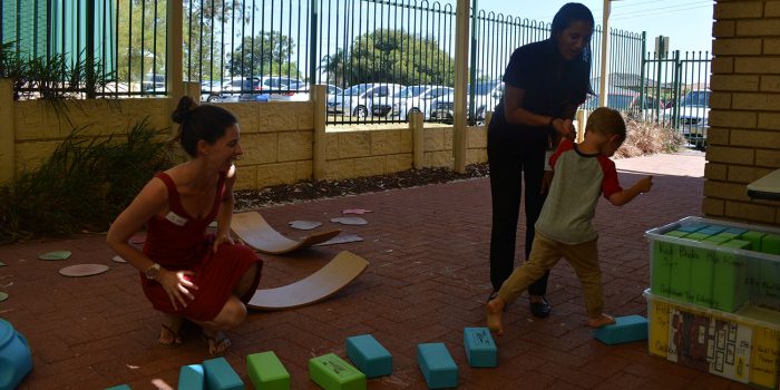 Therapist helps child across stepping stone blocks