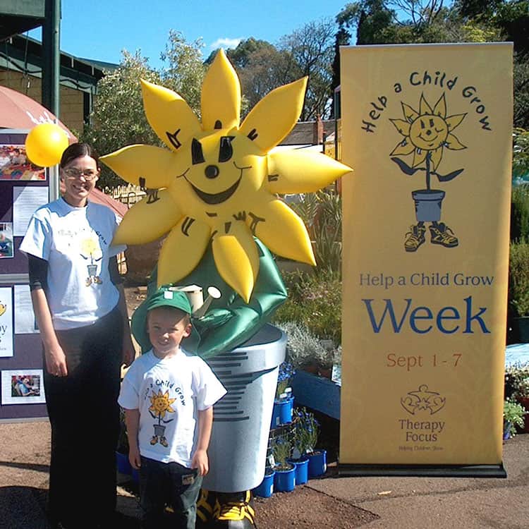 Woman and a young boy standing next to Sunny the Sunflower