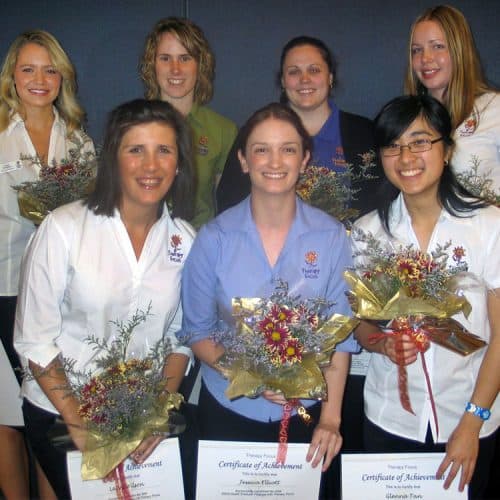 Smiling staff holding their certificates and flowers