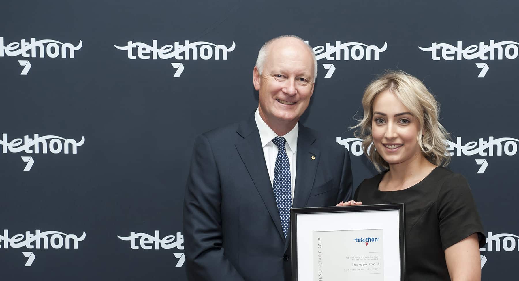 Therapy Focus employee holding certificate with Telethon Chairperson