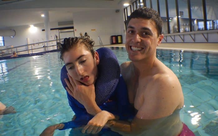 physiotherapist supports boy with cerebral palsy in pool