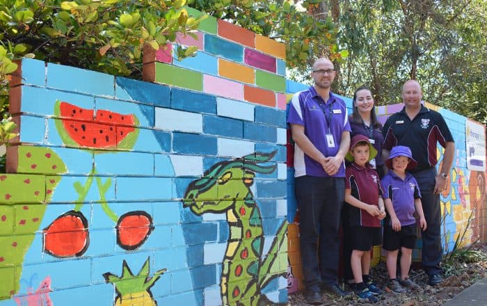 Therapist and children smiling in front of a mural