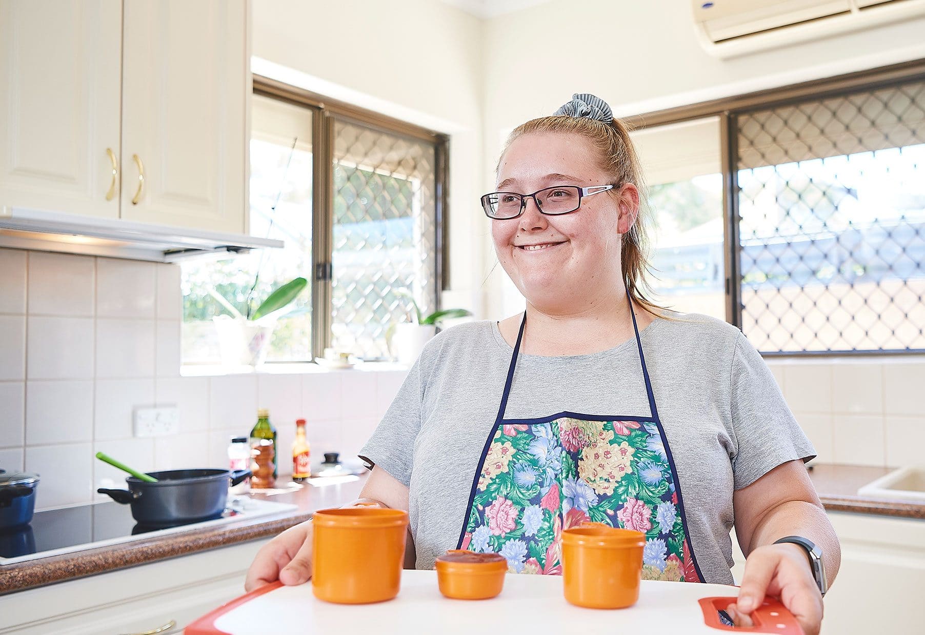 A young woman holding a tray smiling