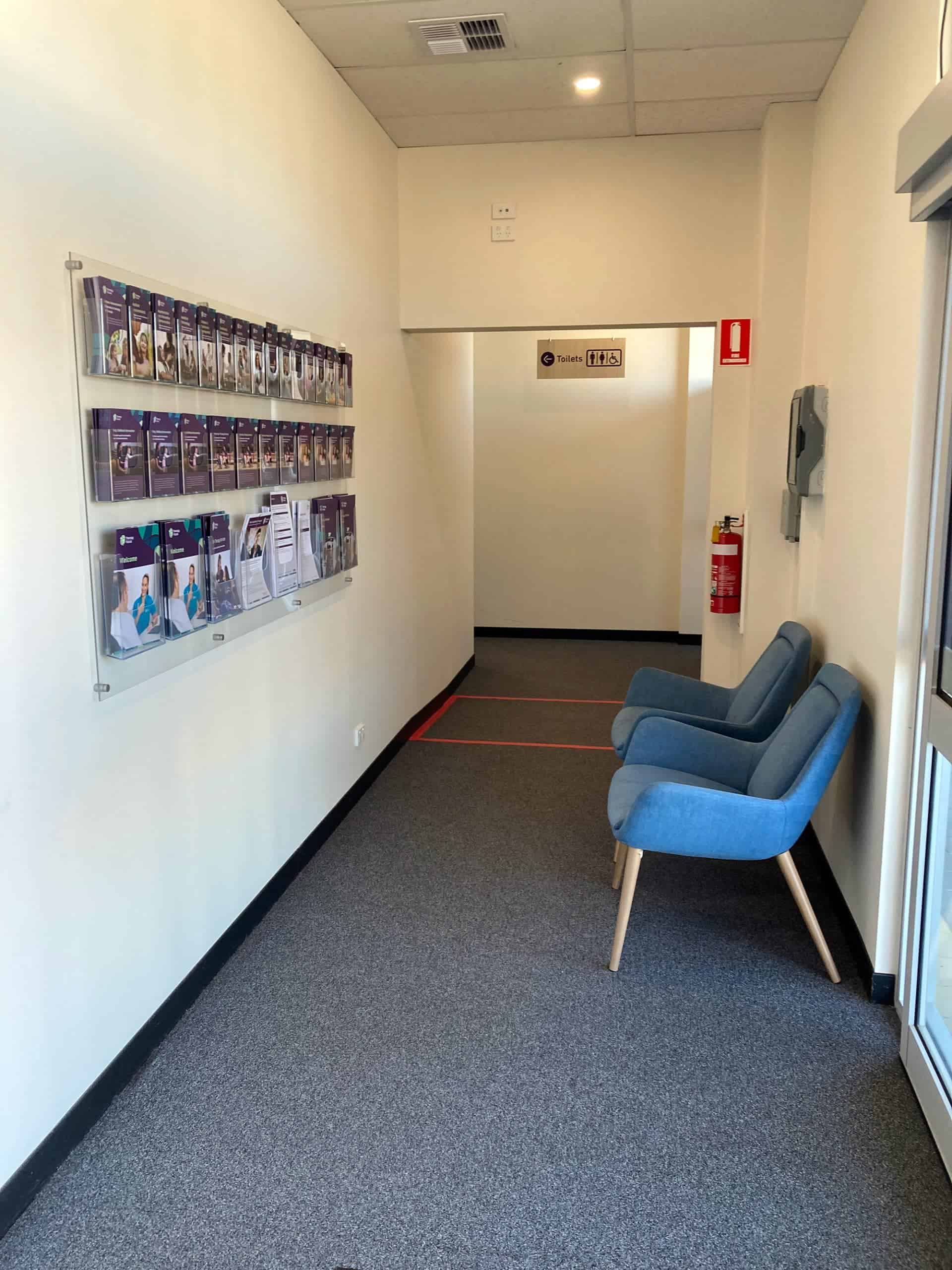 carpeted hallway with brouchers and two blue chairs