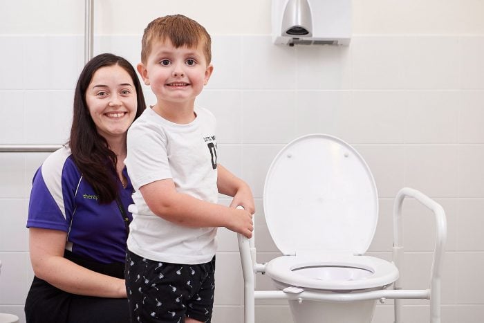 A boy and Continence Clinician standing next to a toilet