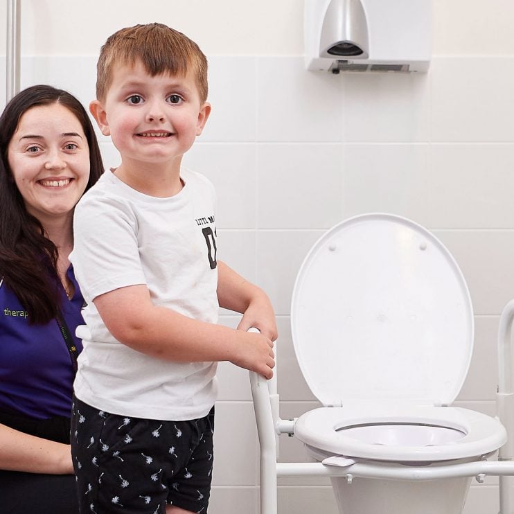 A boy and Continence Clinician standing next to a toilet