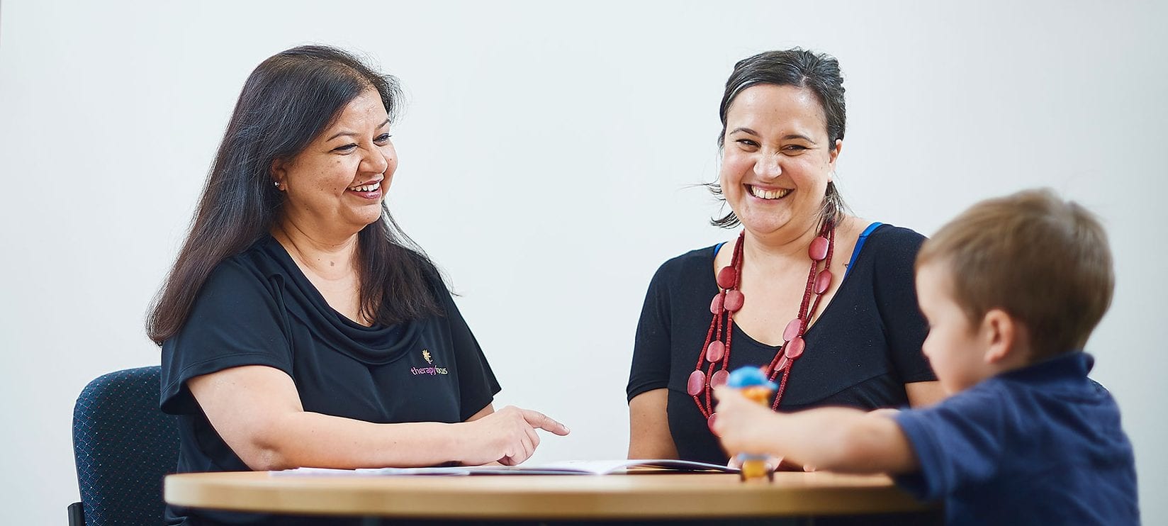 Two ladies smiling at a young boy