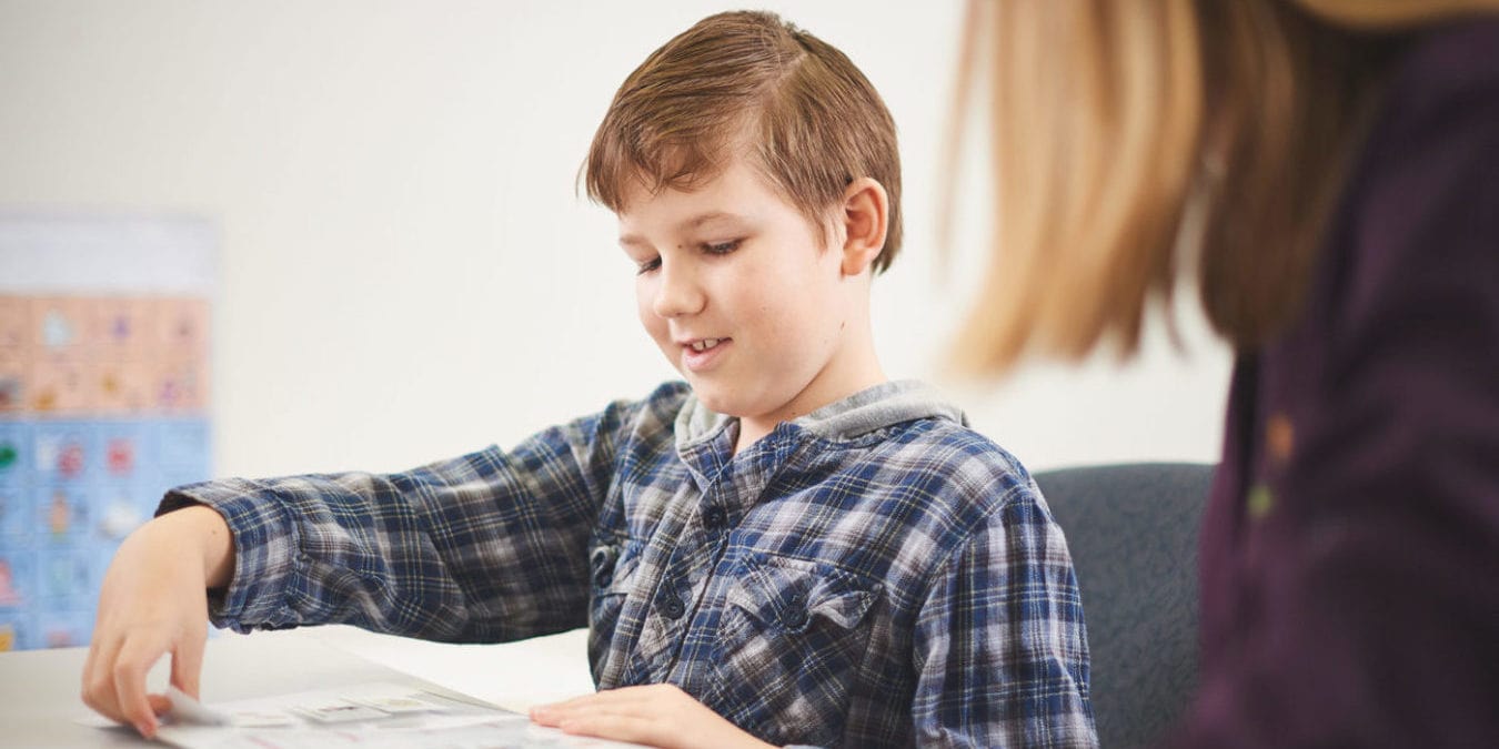 A boy placing symbols on a chart during a speech pathology session