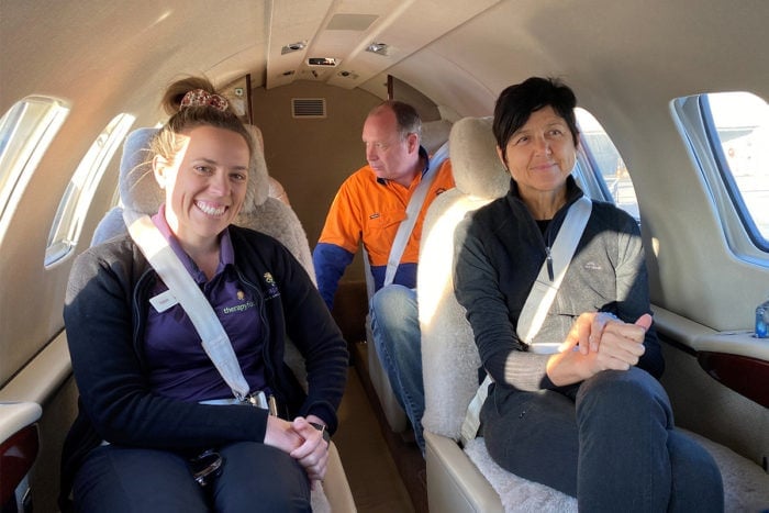 Kelsie and Jane sit in the airplane together. They are smiling for the camera. The aircraft is very small, it is only two seats wide. 