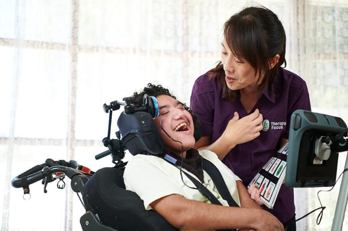 Therapy Focus Advanced Speech Pathologist Ruyi Tong stands with Muji and helps teach her how to use her switch.