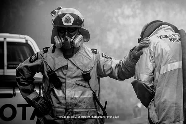 Photo of two firefighters stand together in full uniform and wearing a breathing apparatus.