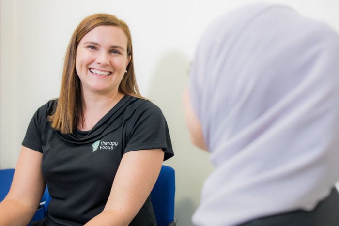 Therapist Emma Marshmann faces the camera and is smiling. Off to the left the back of Therapist Fatema Wali's head is visible.