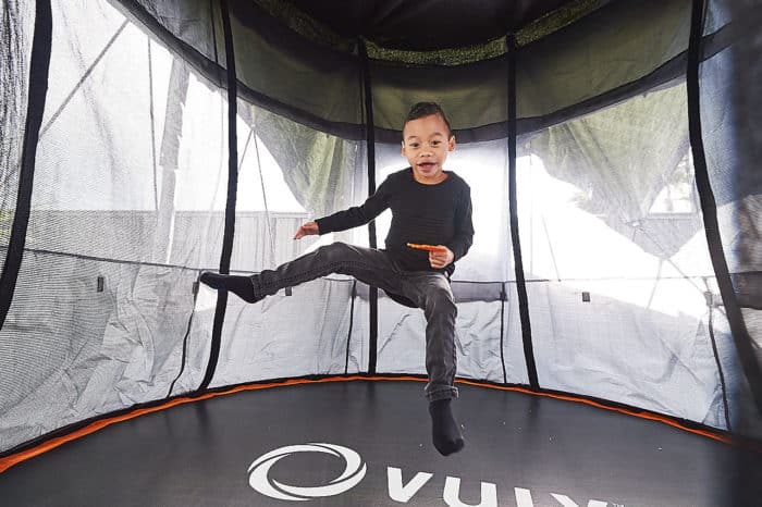 A young boy jumps on a trampoline. 