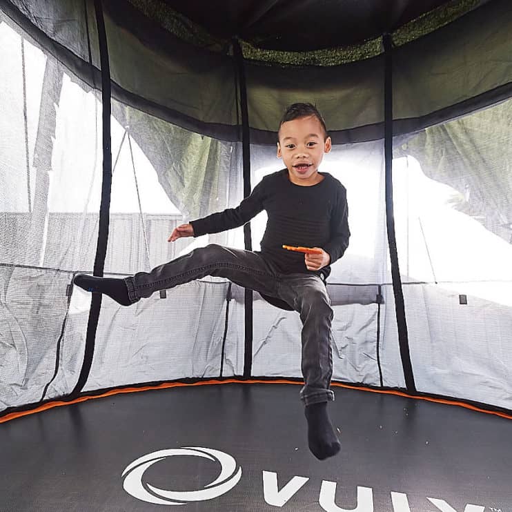 A young boy jumps on a trampoline.