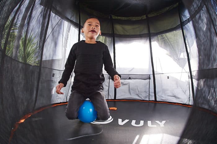 A young boy jumps on a trampoline. 