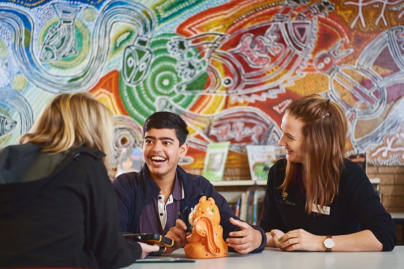 A customer sits with two therapy focus therapists and is smiling and chatting with them.