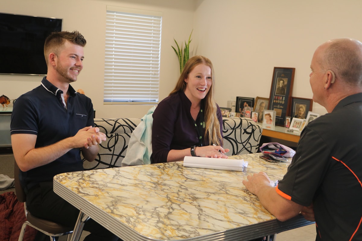 Jason sits at his dining table with Aleysha and the Auslan interpreter.