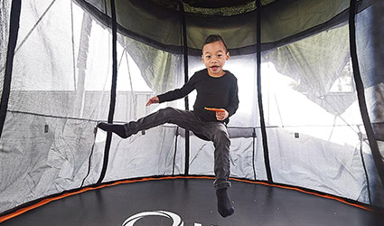A young boy jumps on a trampoline.