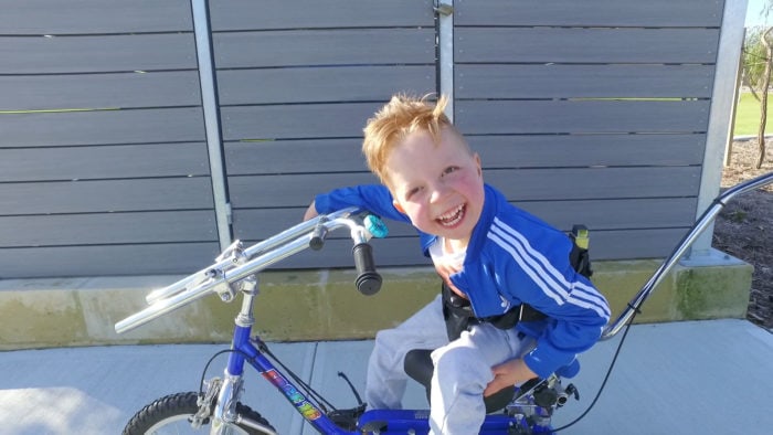 Theo sits on his bike and is smiling.