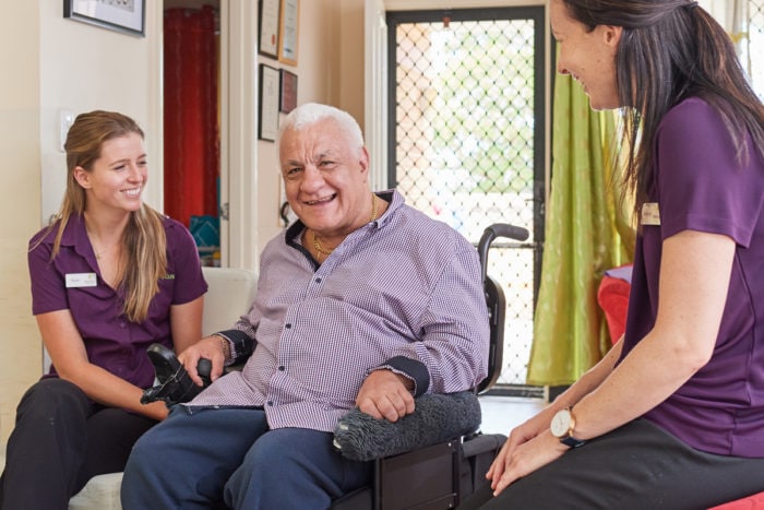 An older man sits with two therapists.