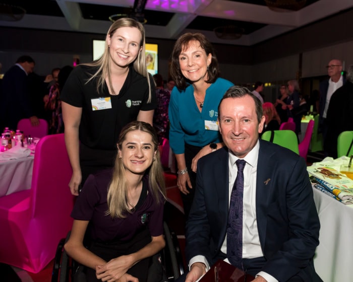 Therapy Focus staff sit and stand next to Western Australian Premier Mark McGowan