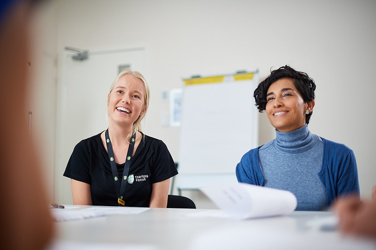 A therapist and parent chat together, smiling.