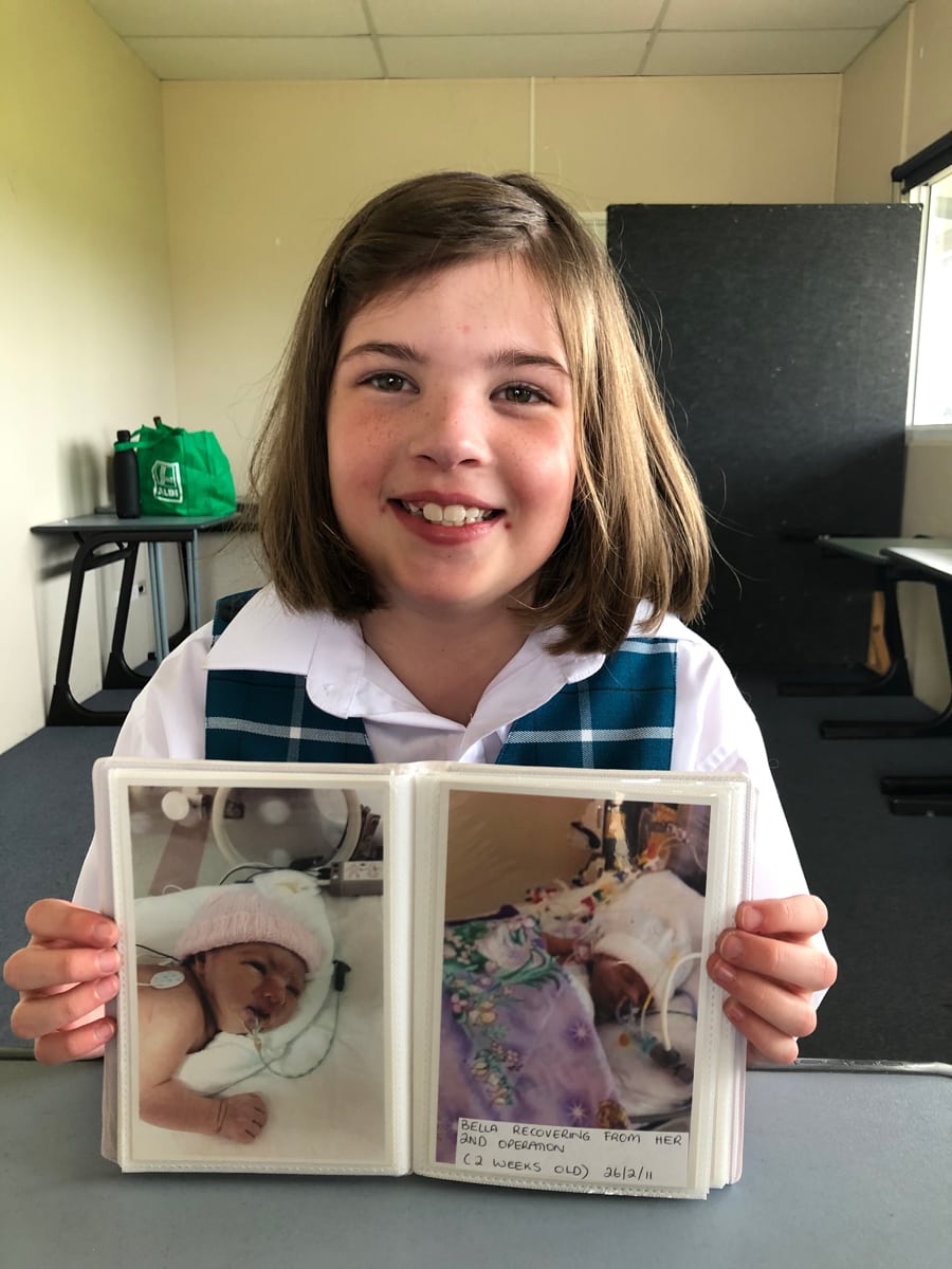 Bella McHarg holding a photo album of her as a baby.