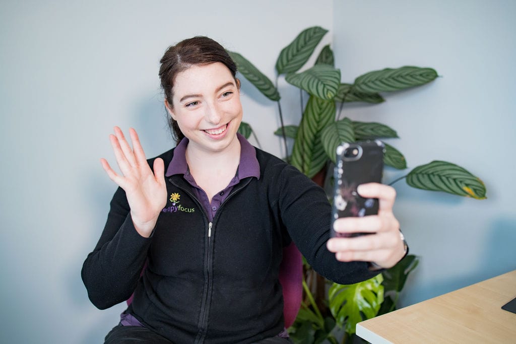 A therapist waving at a camera phone