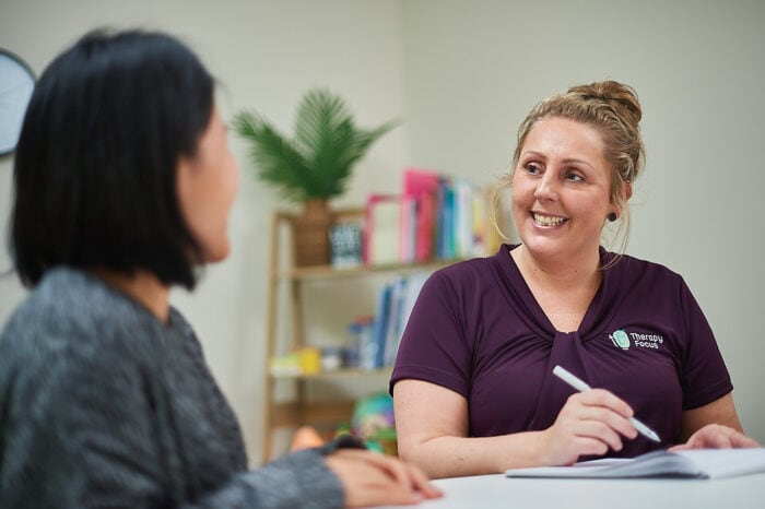 A customer and therapist talk to each other while they sit at a table