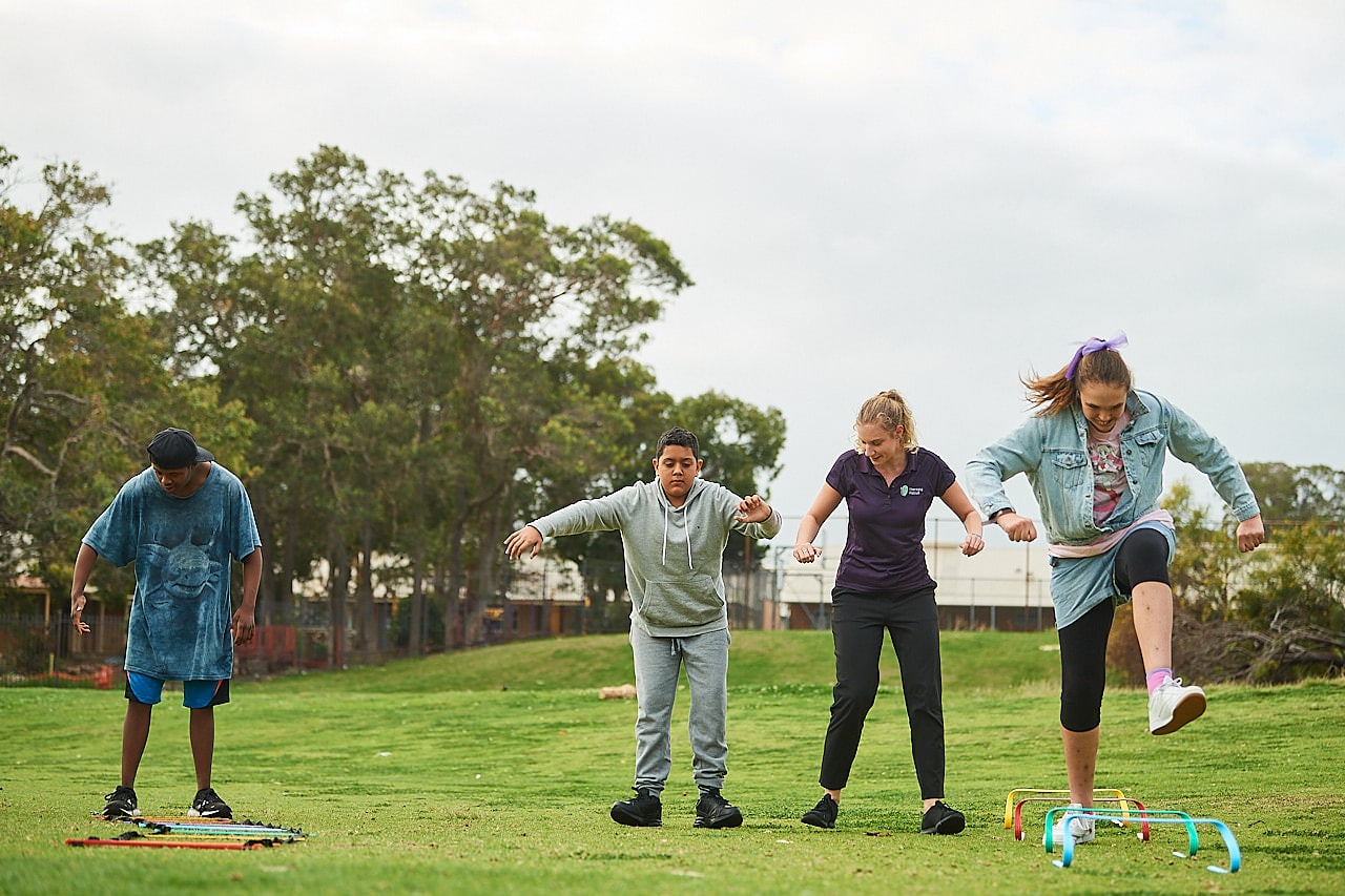 Physiotherapist and 3 teenagers do exercises in a park.