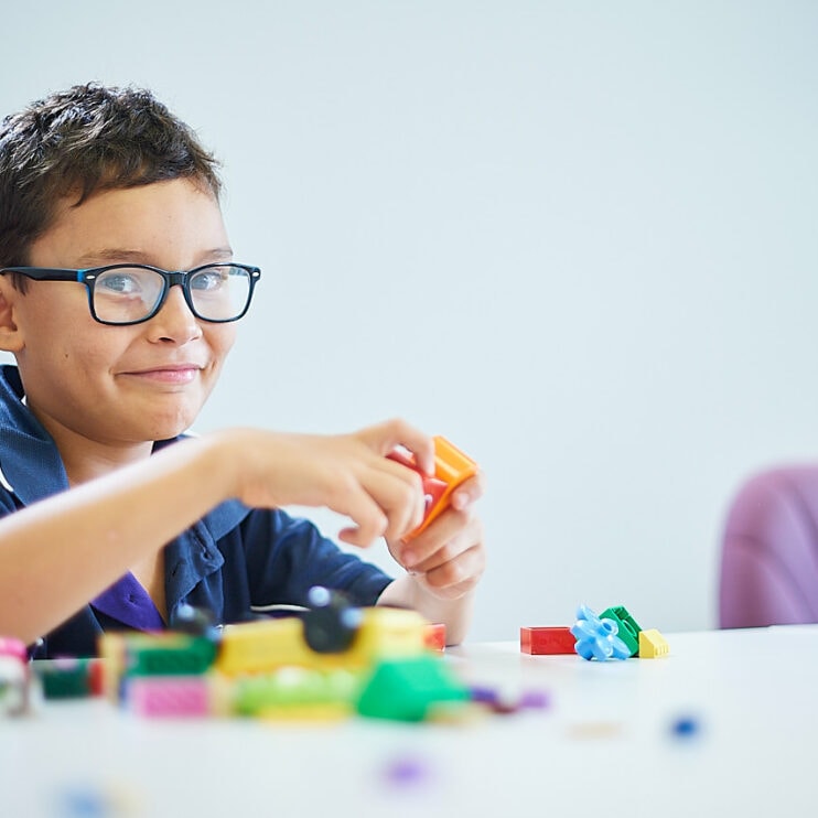 A young boy playing with Lego smiling