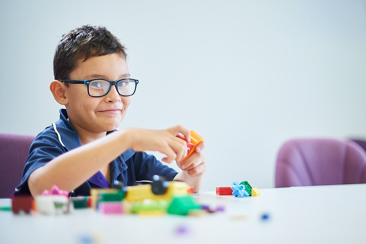 A young boy playing with Lego smiling