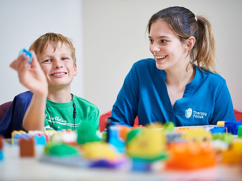 Therapist smiling at a boy holding LEGO